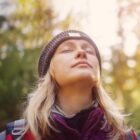 Woman with closed eyes looking up at the sun, symbolizing peace, healing, and resilience.